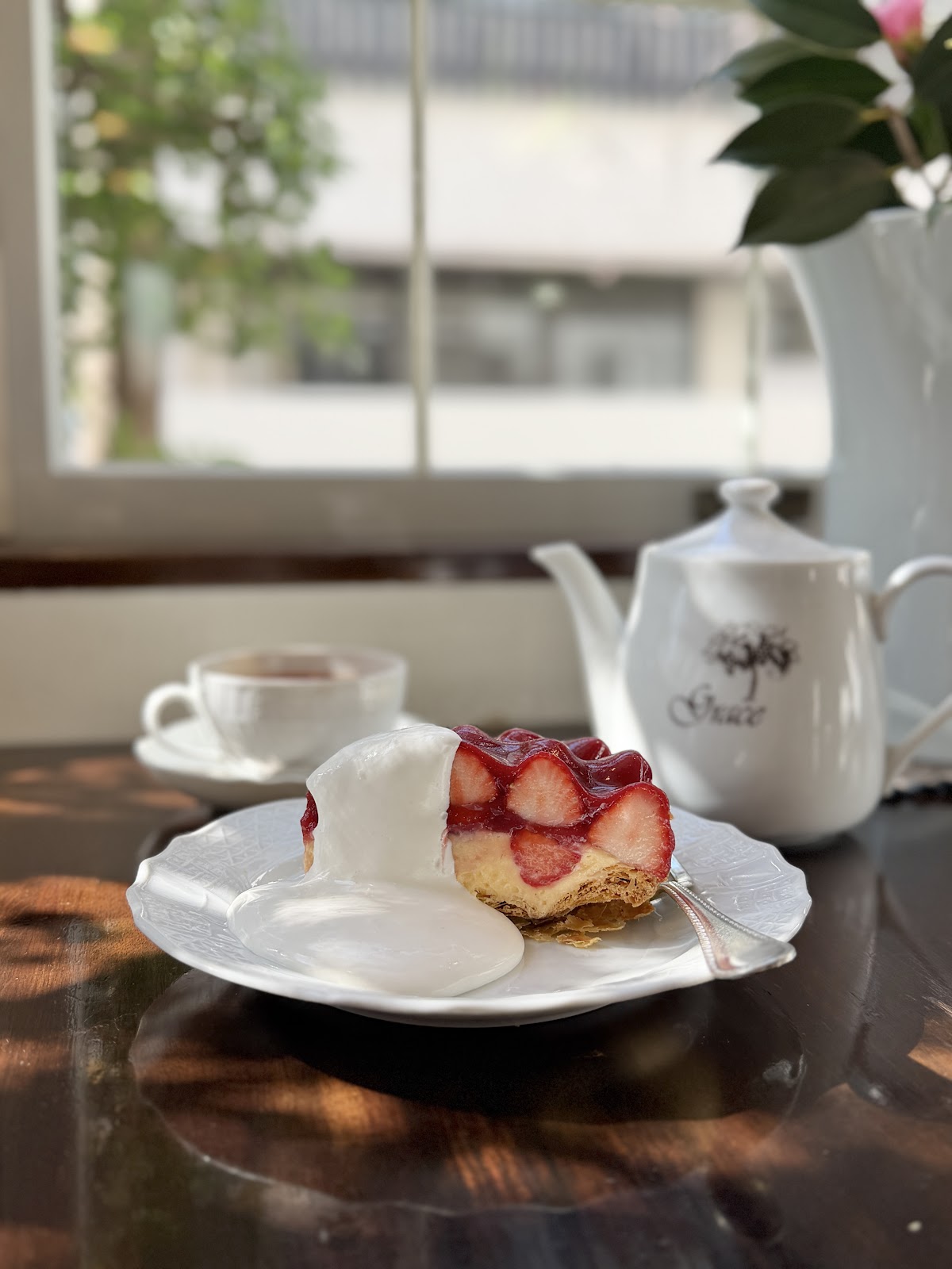 窓辺の席に置かれたいちごのパイと、Grace 印の紅茶ポット。